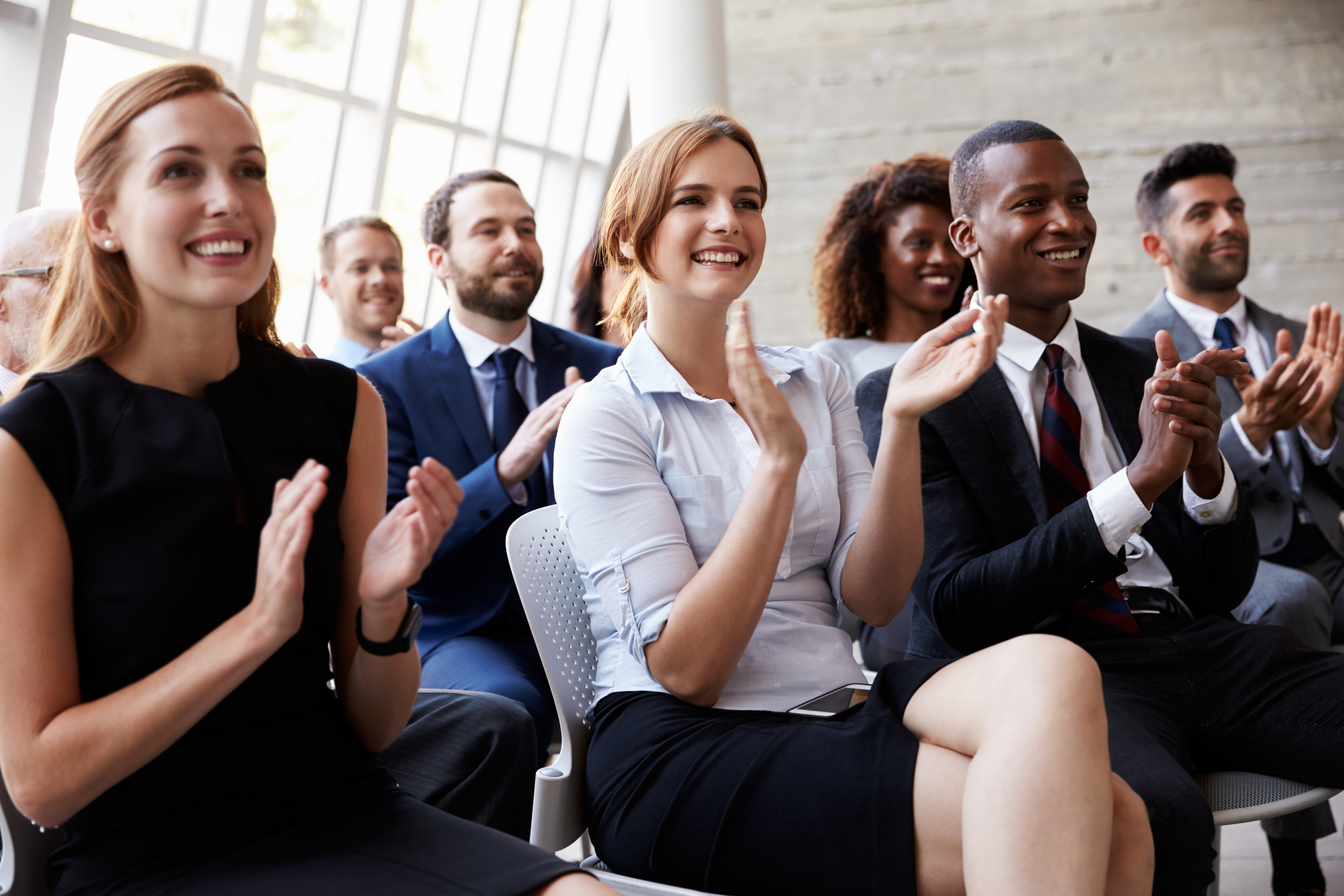 A diverse audience enthusiastically applauds during an event