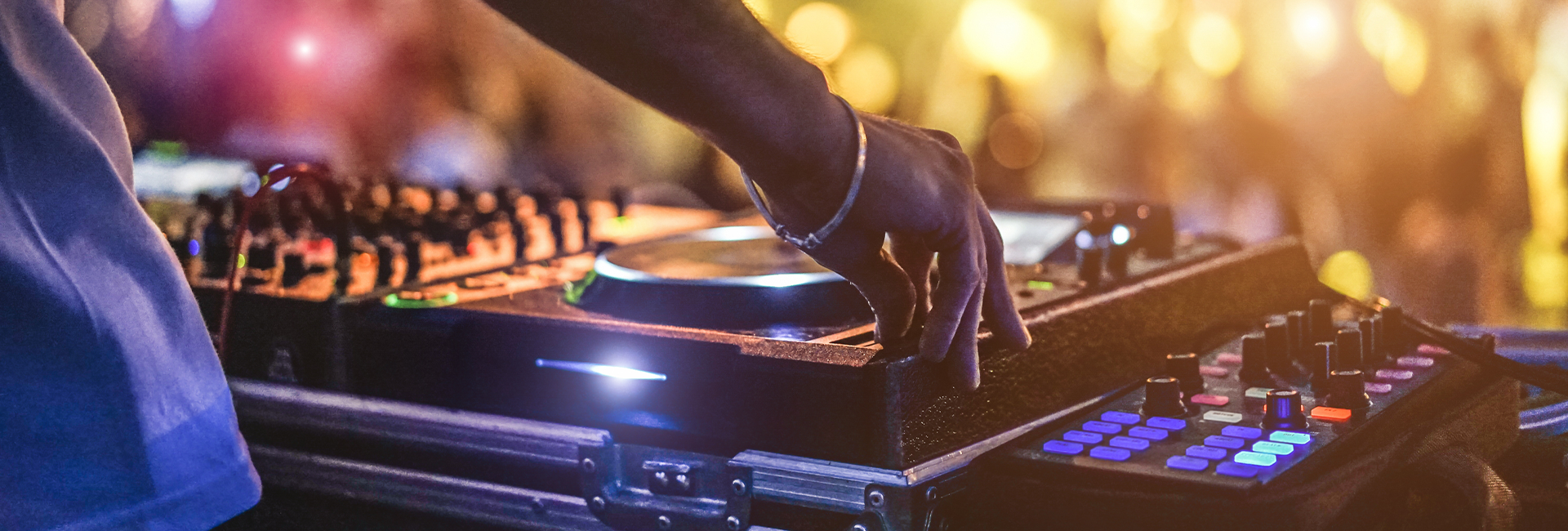 DJ adjusting controls on a mixer during a lively performance
