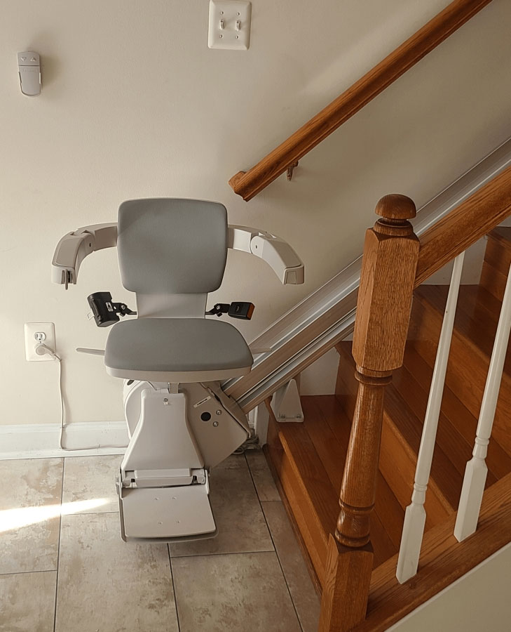 A stairlift installed on the left side of a wooden staircase. The stairlift is a Bruno SRE 3050 with a carrying capacity of 350 lb. It is in Chevy Chase, MD