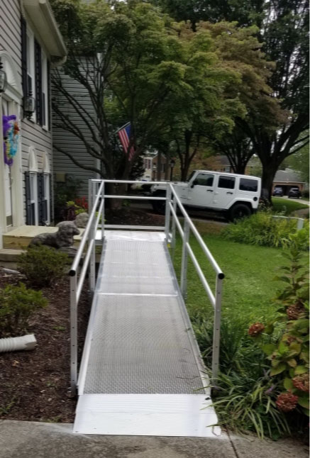 A wheelchair access ramp with railings on both sides, and landing on the sidewalk from the backdoor of a house in Rockville, MD