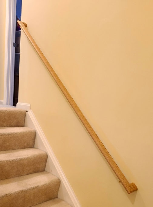 This image is a well stained and polyed oval wood railings with returns, installed in a home in Potomac, MD.