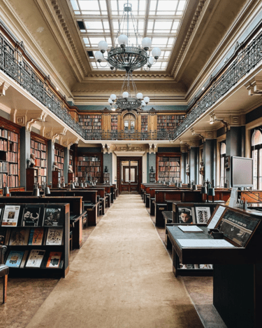 An image of the sort of library that scholars of medieval literature might use, with high ceilings, skylights, and bookshelves even on a second story.