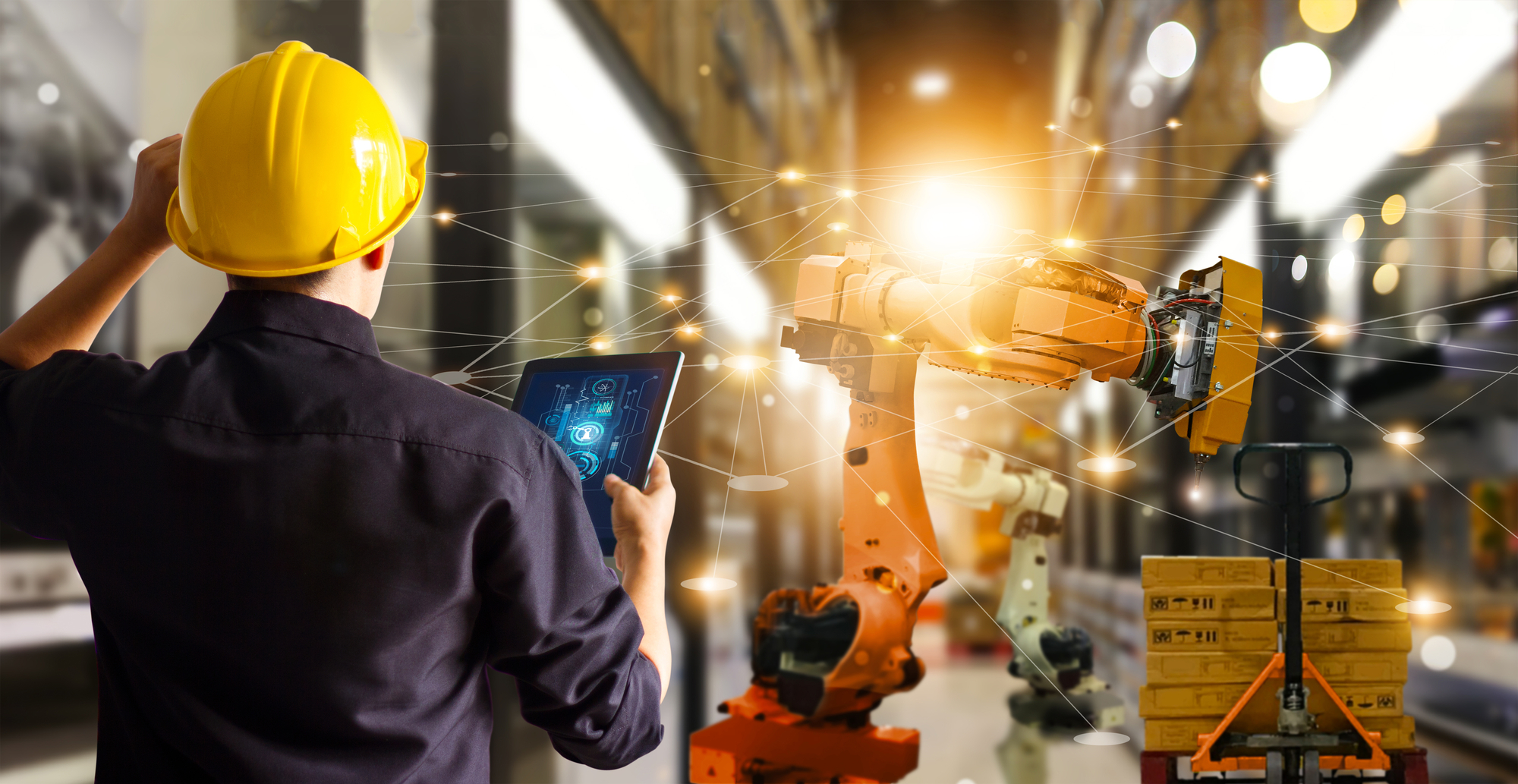 A man in a hard hat observes a robot, showcasing a blend of human oversight and advanced technology.