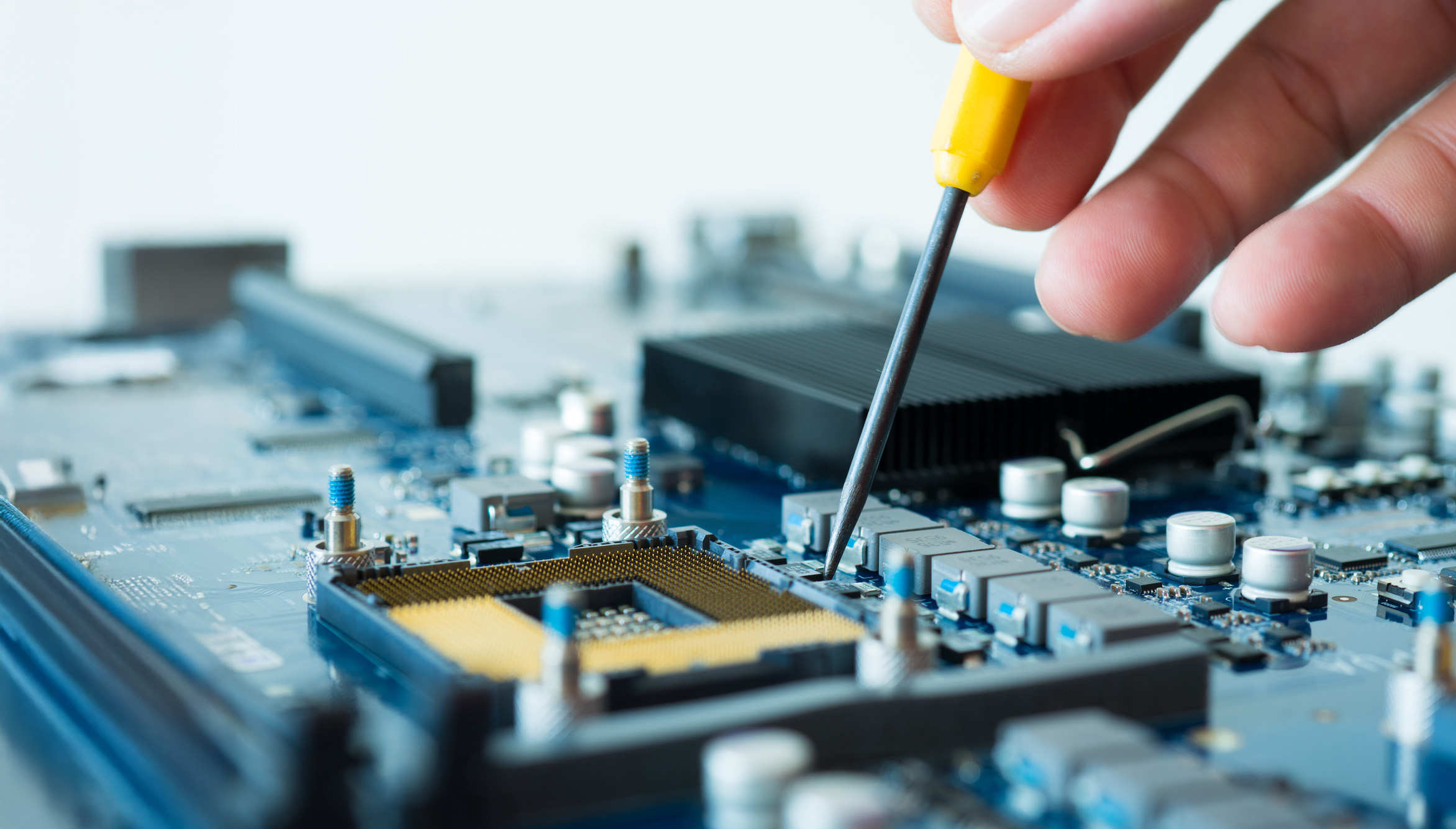A person using a screwdriver to repair a circuit, focused on their task in a well-lit workspace.
