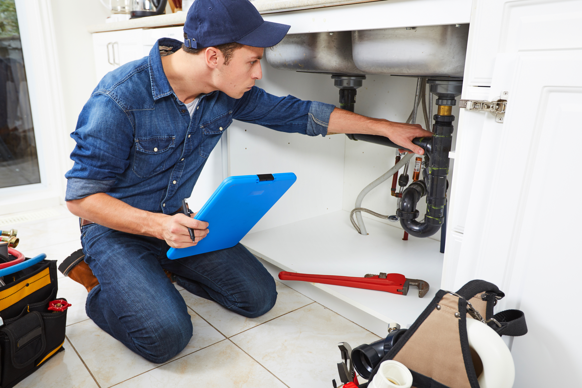 A Person Kneeling on the Floor in Front of a Kitchen Sink.