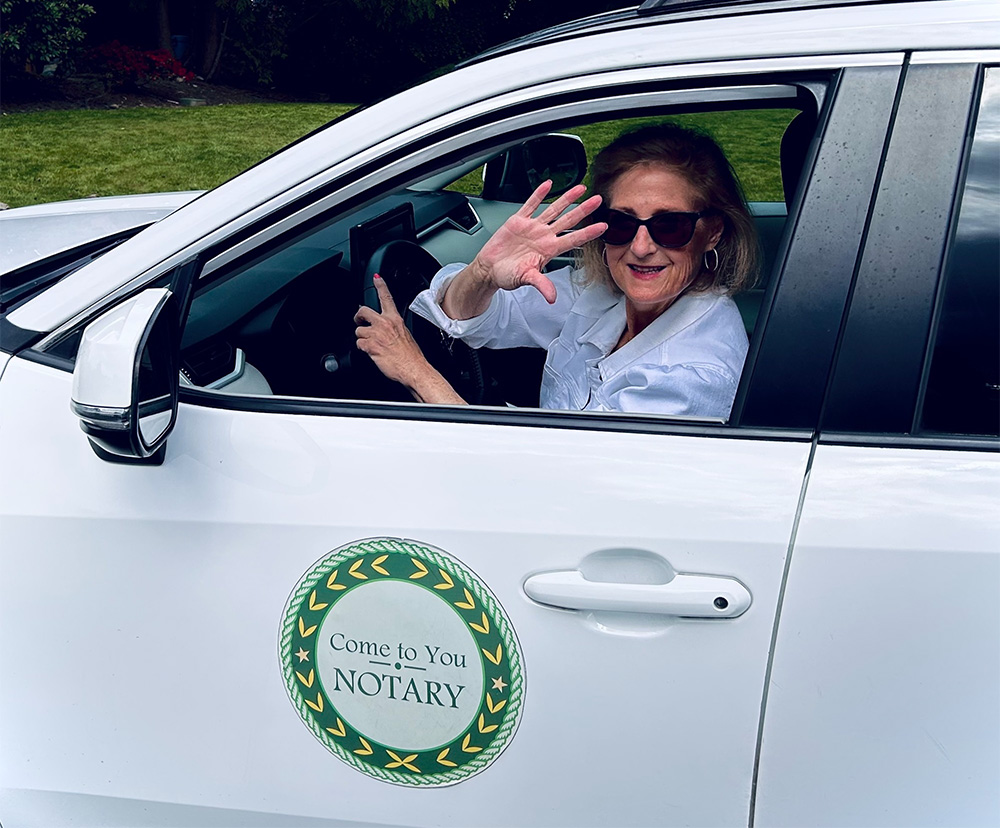 A woman in a white car with a "Come to You Notary" sign.