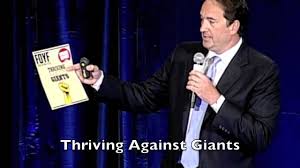 A man displays a sign that says "Thriving Against Giants,"