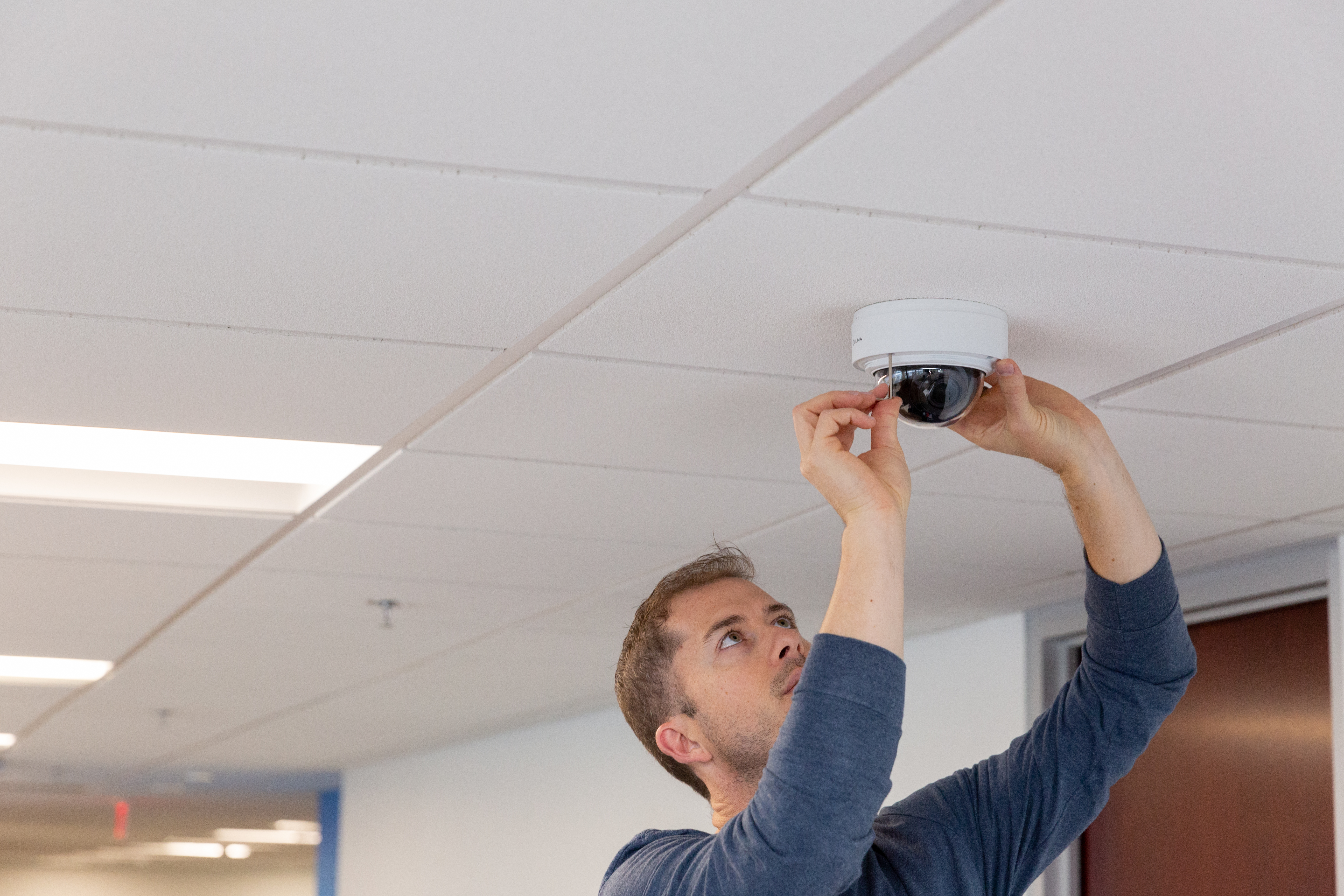 Techinician installing a Luma Surveillance camera in an office