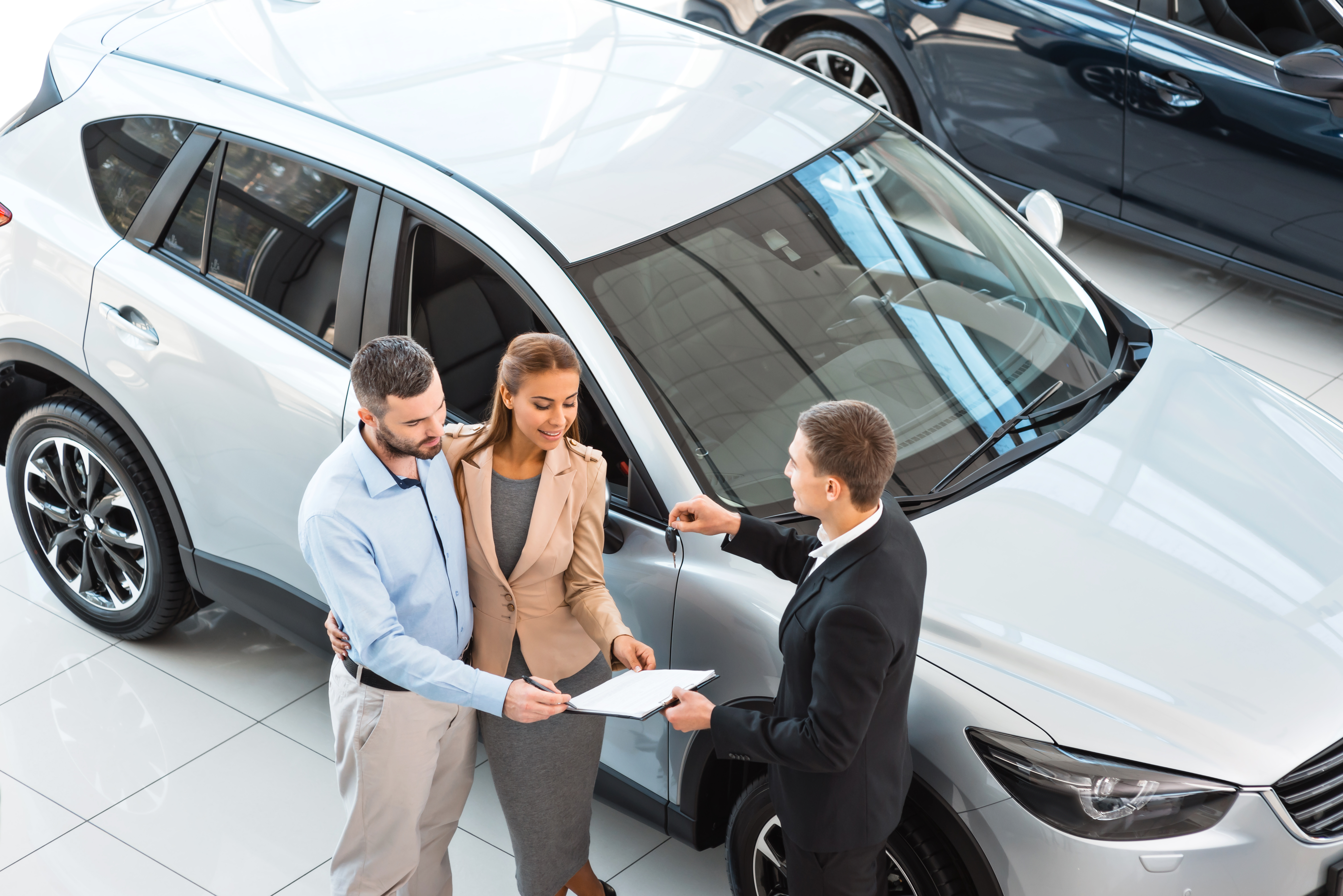 Salesman And Buyers Reviewing Contract For A New Car