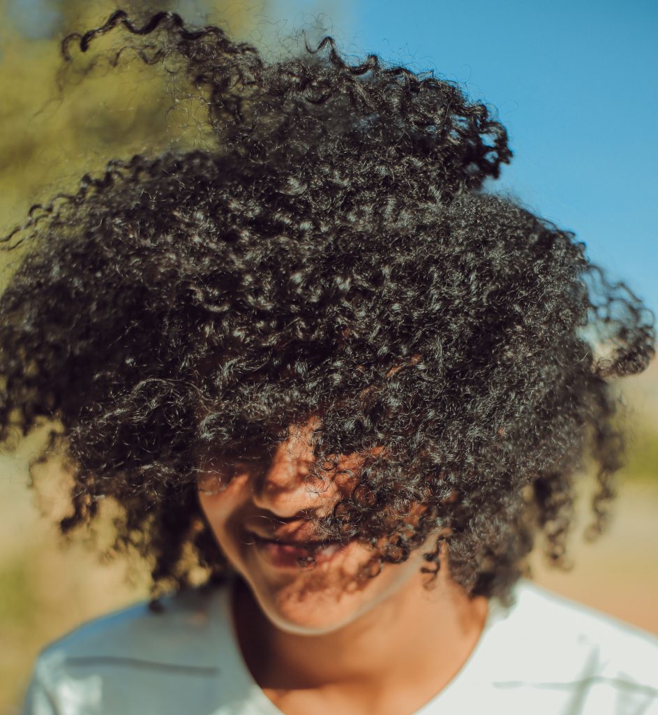 Girl with curly, textured hair with her hair blowing in her face