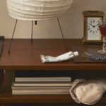 nightstand with eye mask, night cream, clock, and lamp