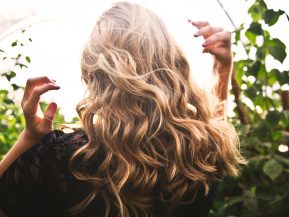 Back of woman's head with blonde hair surrounded by greenery