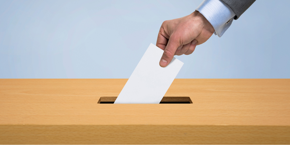 hand putting a ballot in a box