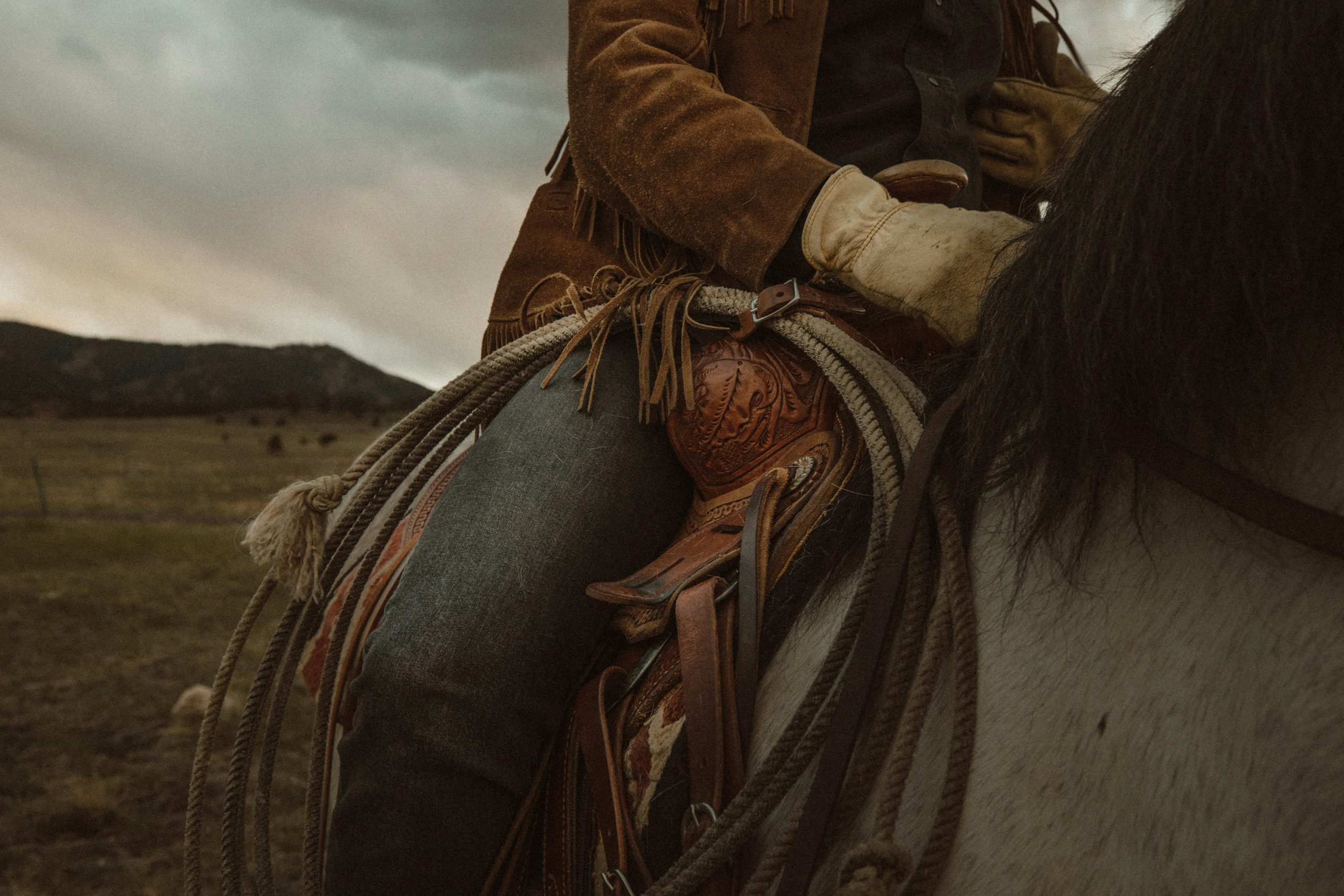 A close-up of a person riding a horse in a Western landscape.