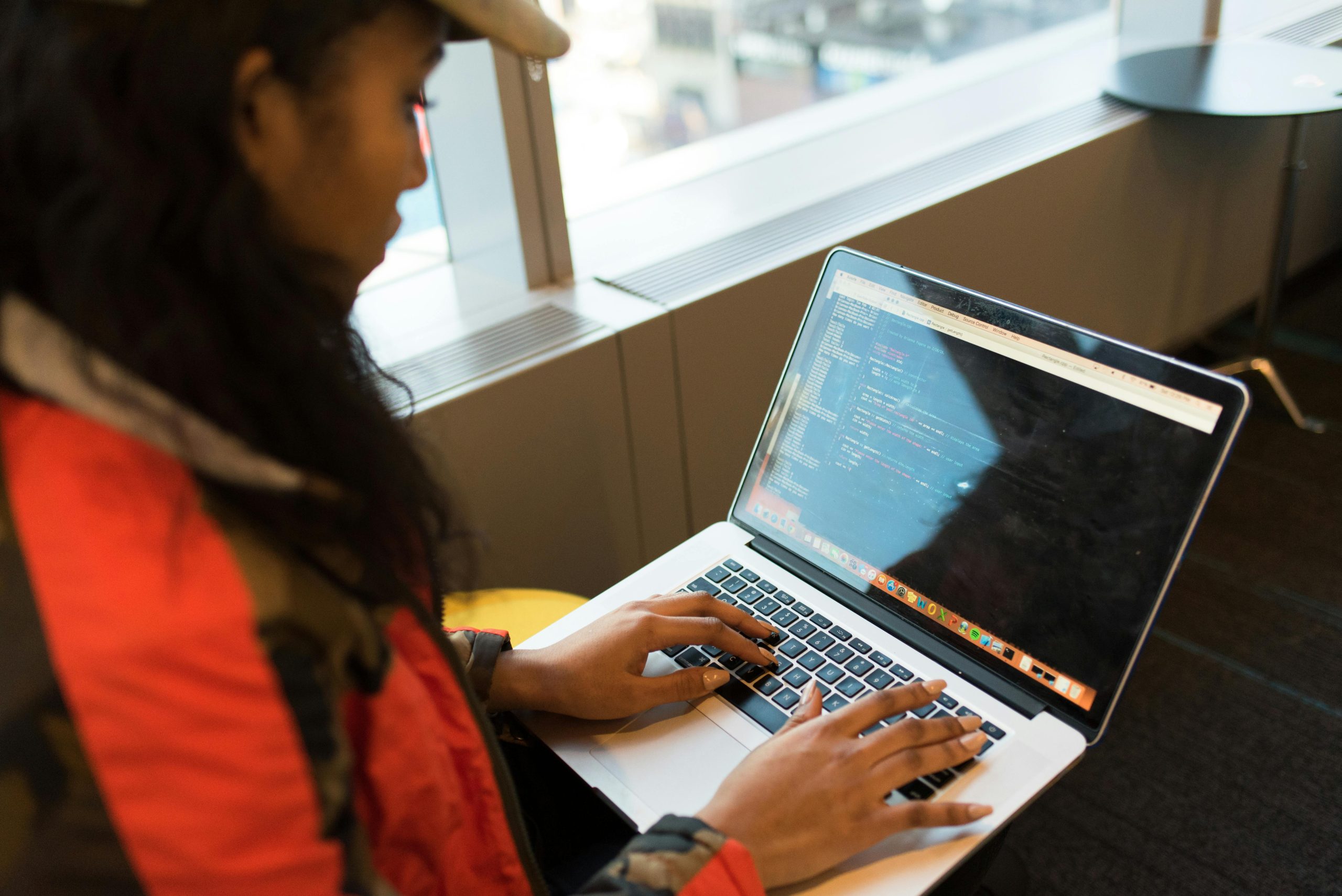 A person works on a laptop computer showing code on the screen.