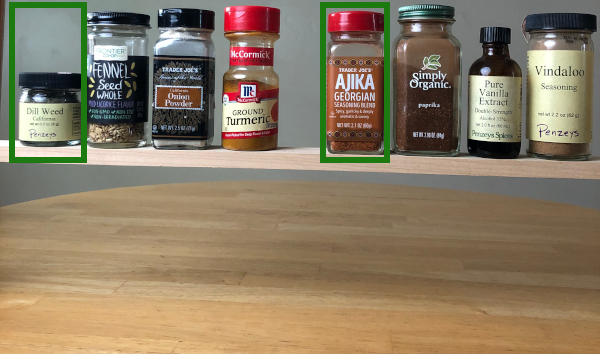 A row of 8 spice jars on a wooden shelf. The dill weed and ajika are outlined in green rectangles.