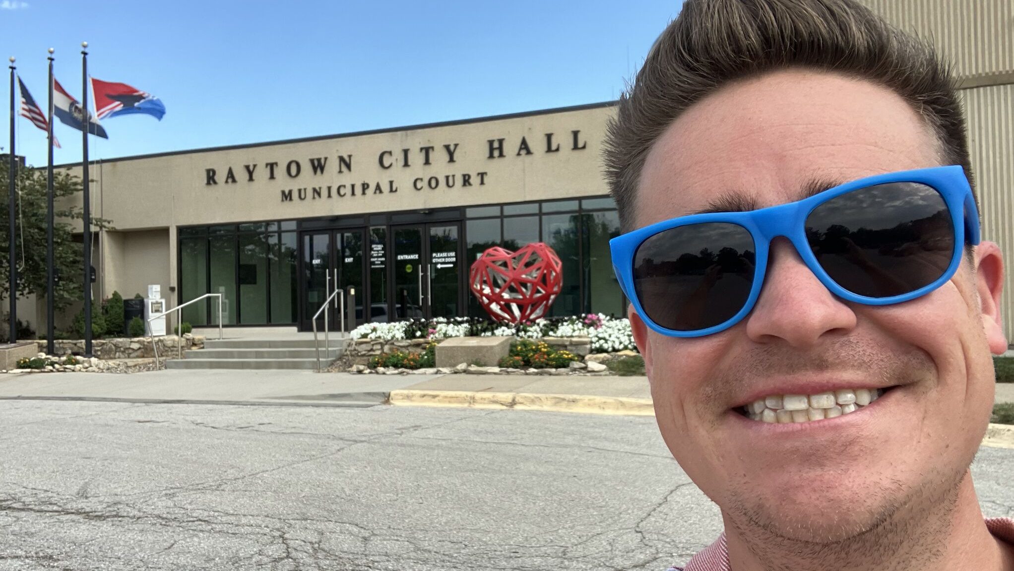 Joey Carley takes a City Hall Selfie in front of Raytown, Missouri, City Hall, where the city flag he designed flies on a flagpole in front of the building.