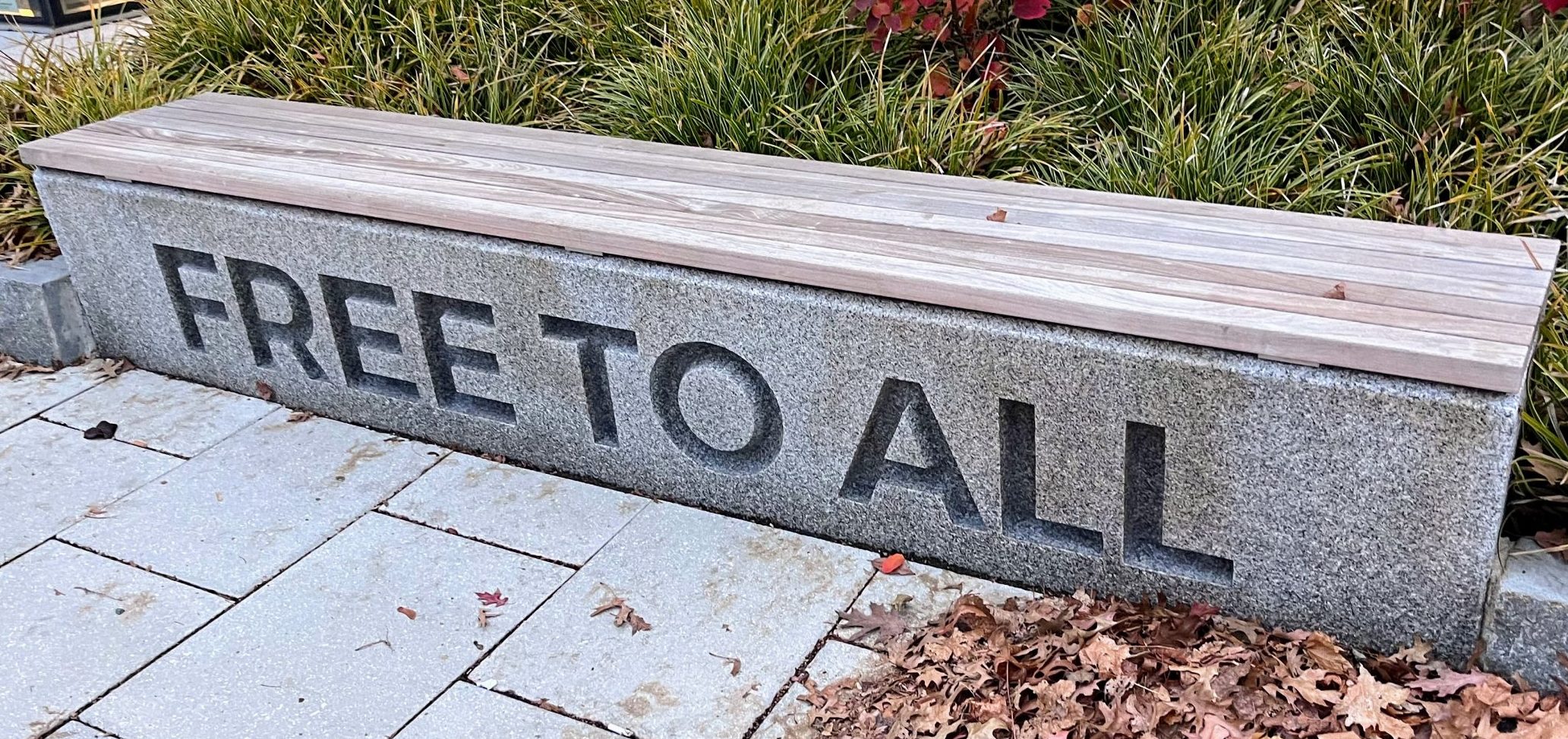 A granite bench with the words "Free to all" etched into the front surface.
