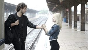 Sad teenage couple saying goodbye on train station platform