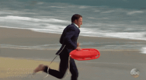 Man running into ocean with lifesaver