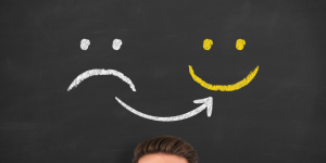 Stock photo of chalkboard with sad face and smiley face drawn in chalk