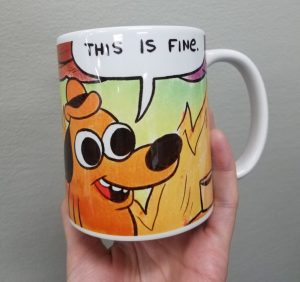 Mug with the "This is Fine" meme with a cartoon dog sitting at a table on fire