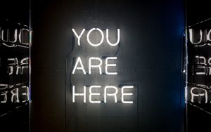 A neon sign reads "You Are Here."