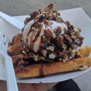 waffle topped with ice cream, hot fudge and nuts