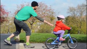 Dad teaching kid how to ride bike