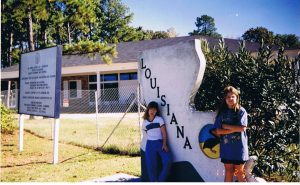 Two very disgruntled young women in front of the Louisiana State sign