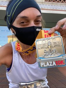 A woman holding up a 10k race medal