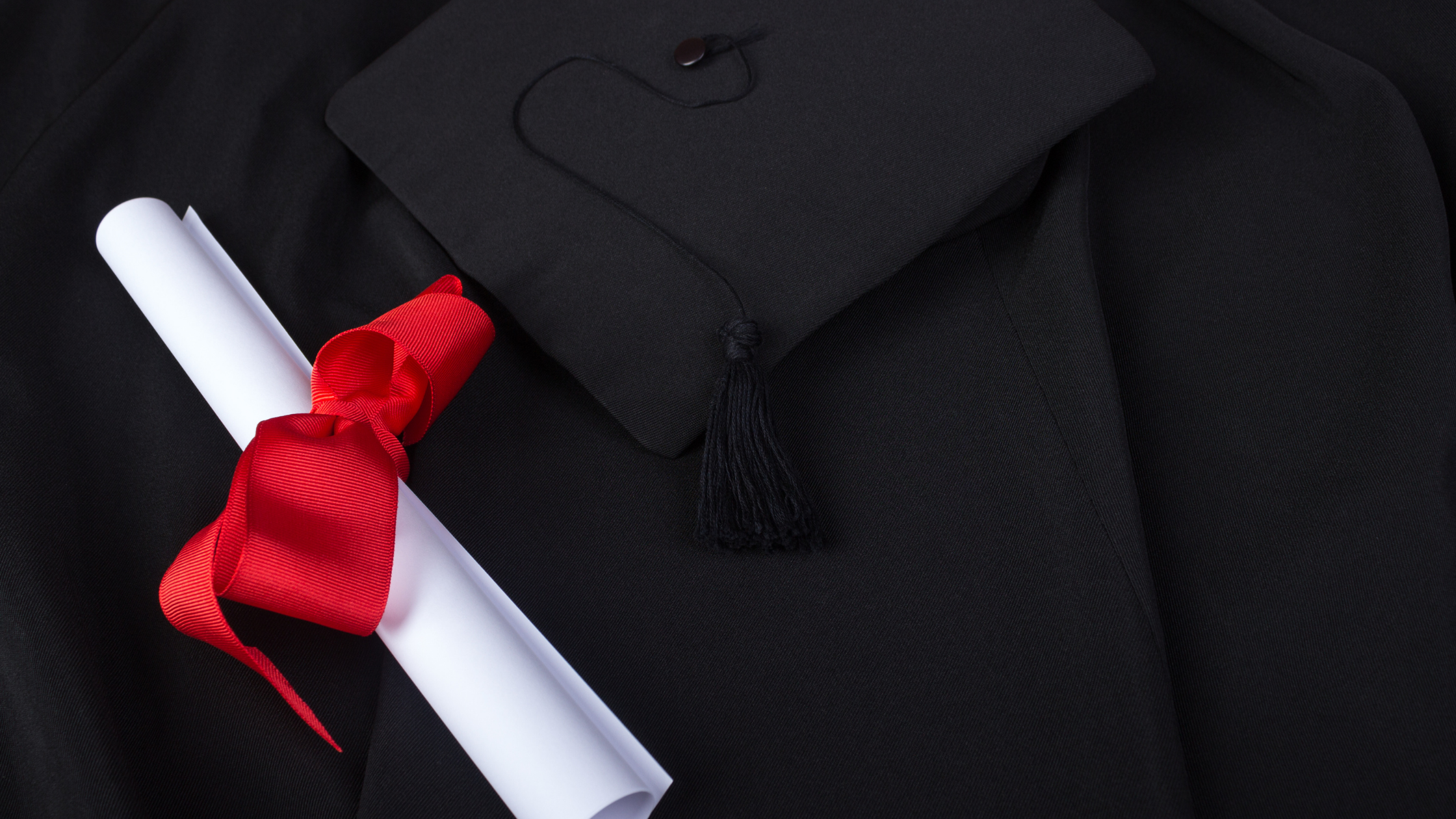 Image of diploma with red ribbon and graduation cap