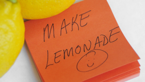 Two lemons with a sticky note that has a handwritten note that says "Make Lemonade" and a smiley face.