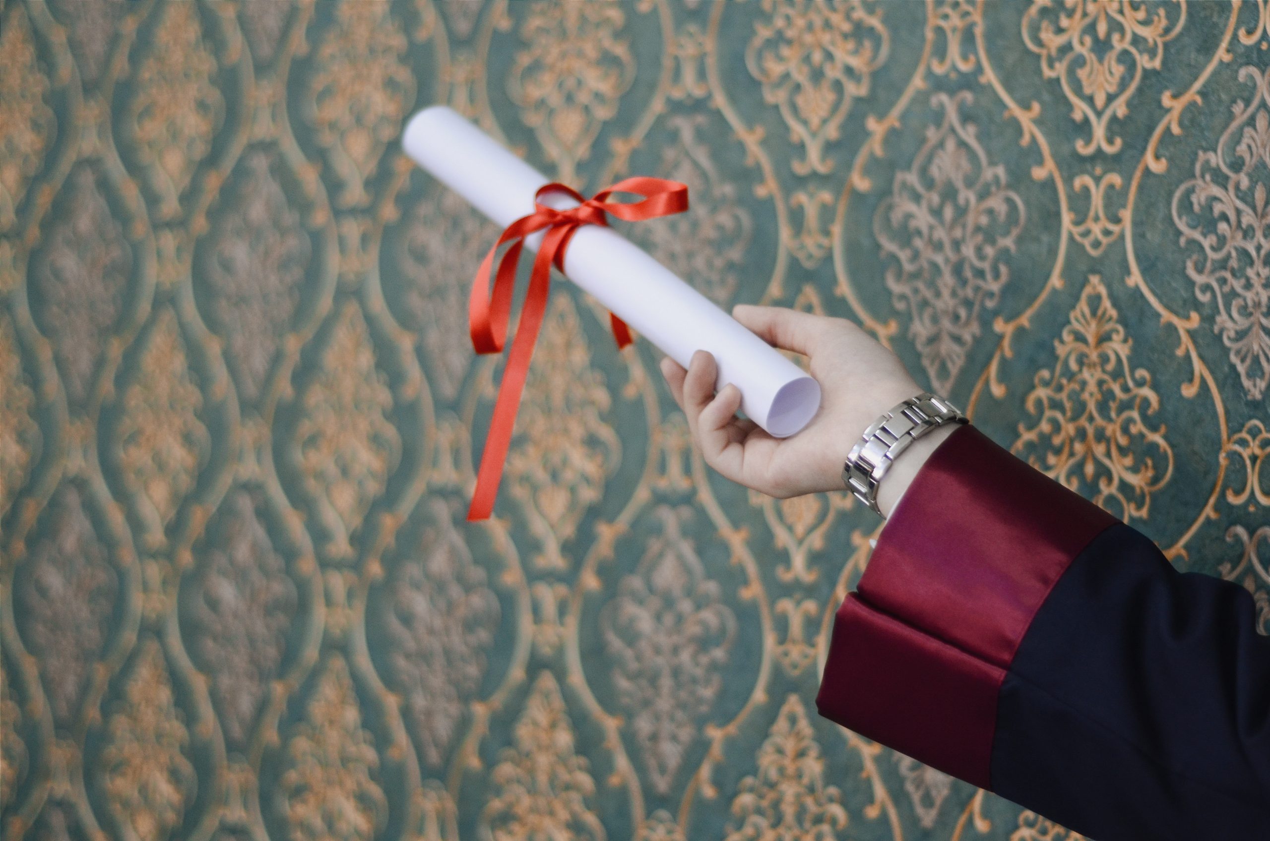 arm holding a diploma with a ribbon