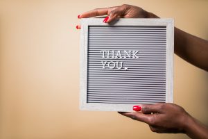 Female hands hold a sign board with the text Thank You in small letters.