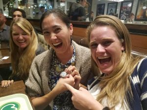 Kendra and Sarah holding a shiny championship ring and laughing