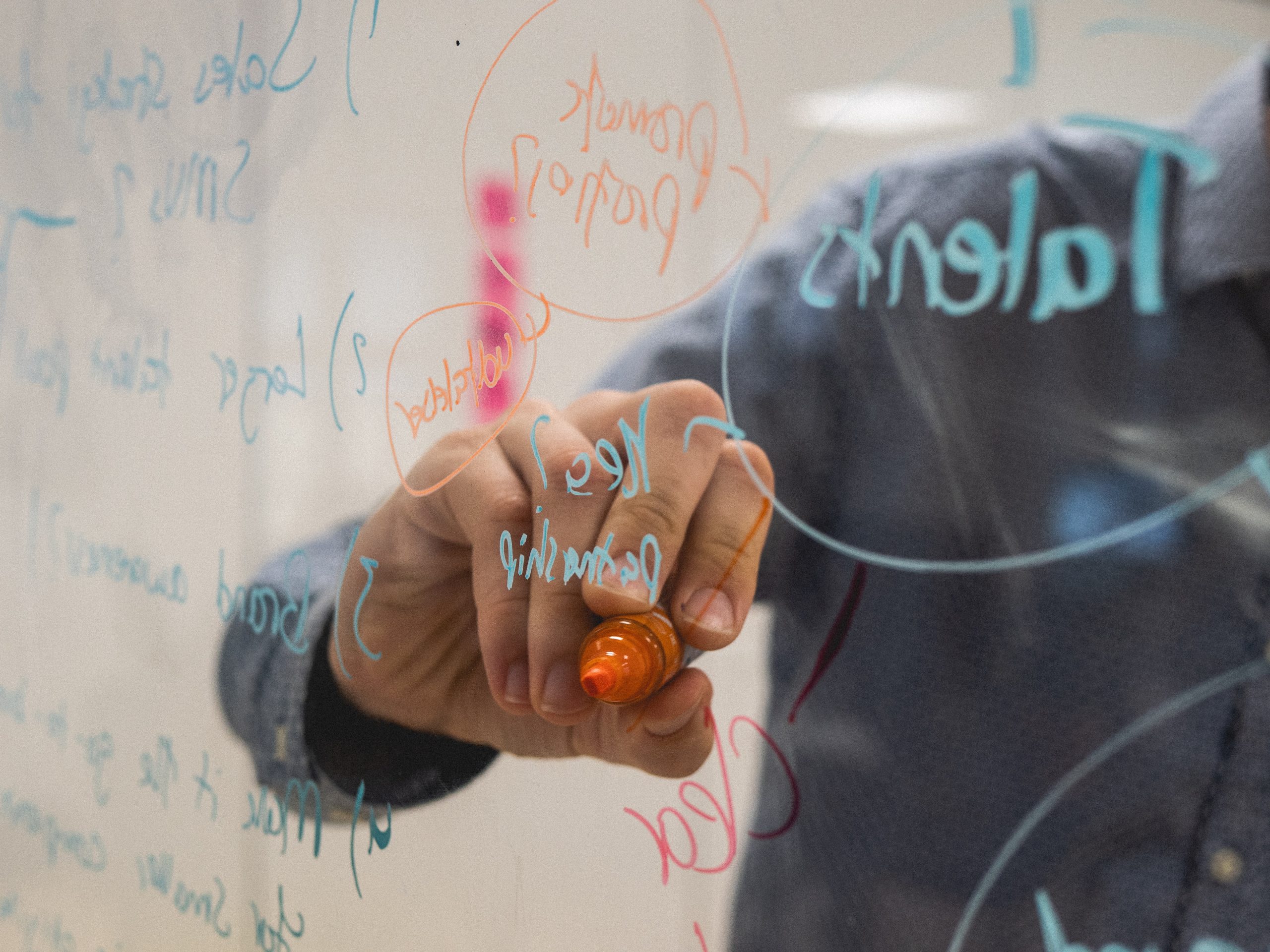 person writing on clear whiteboard