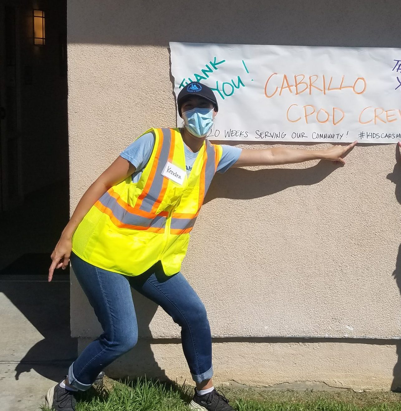 Employee in a yellow safety vest pointing to a handmade Thank You sign