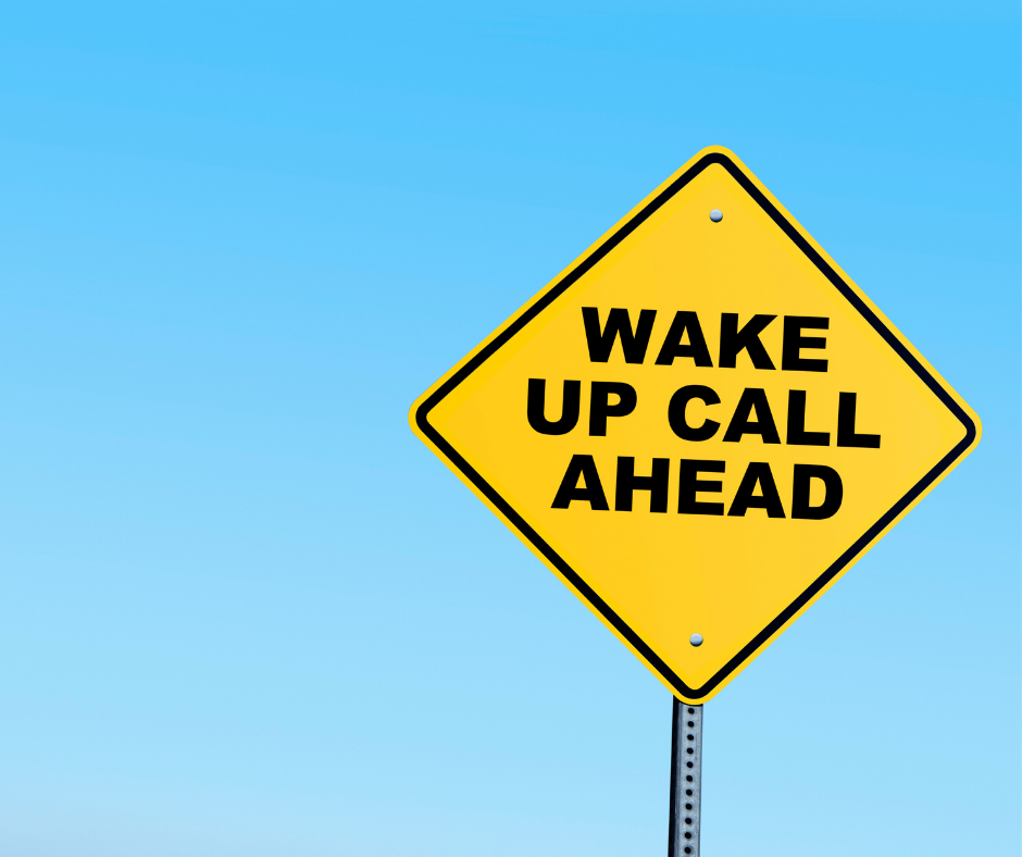 Yellow signs with black text that says wake up call ahead