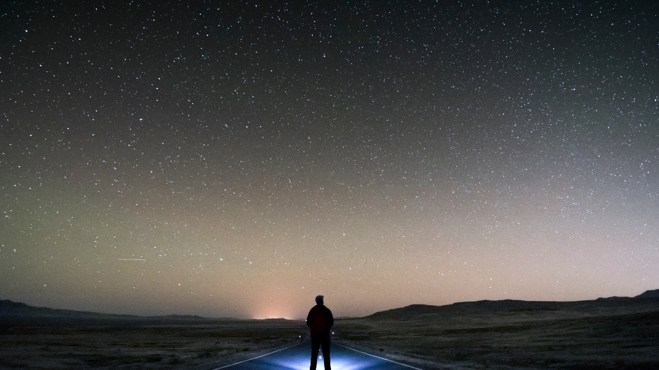 person standing in the road at night with stars