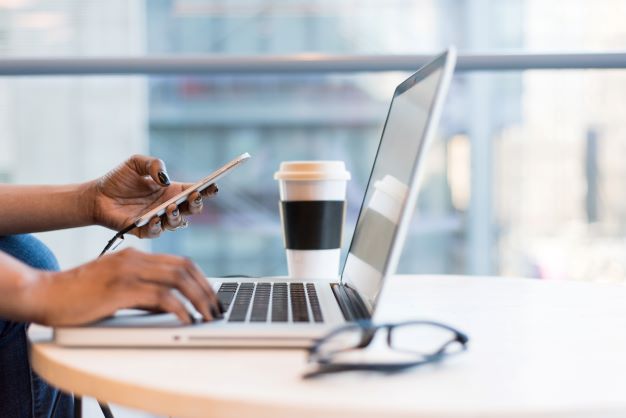 person typing on laptop while using phone