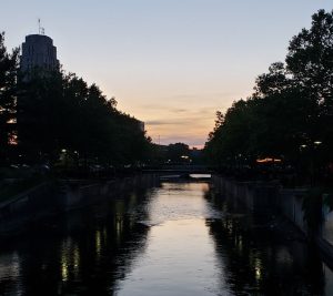 Sunset over a river with tree and building silhouettes on both sides