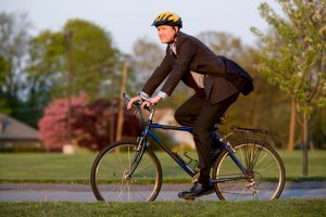 man rides bike in a suit