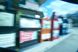 A row of newspaper boxes on a sidewalk, blurred by a camera effect.