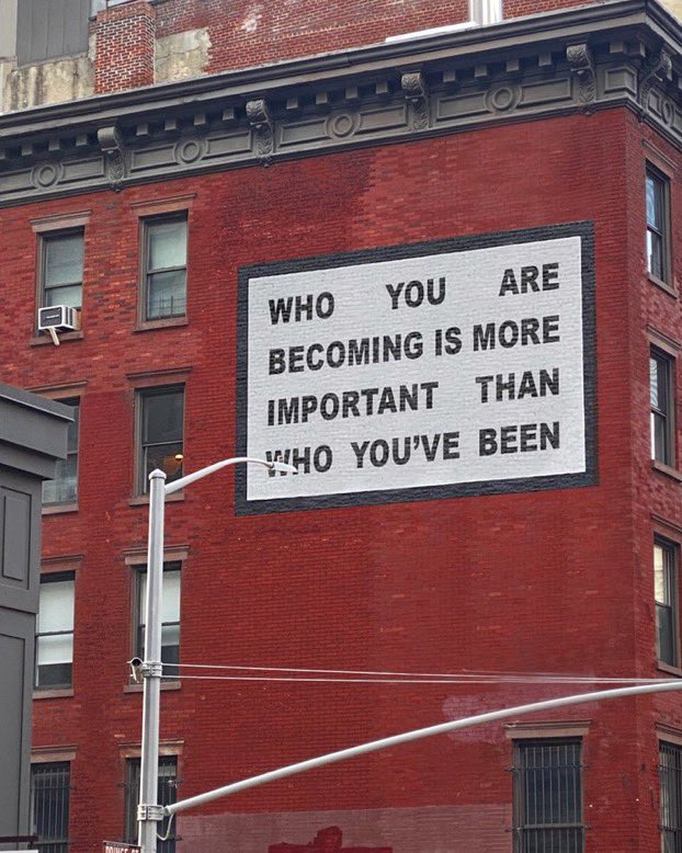 picture of a building with a sign that says who you are becoming is more important than who you've been