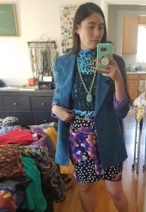 A woman taking a selfie in a mirror wearing lots of colors and patterns.