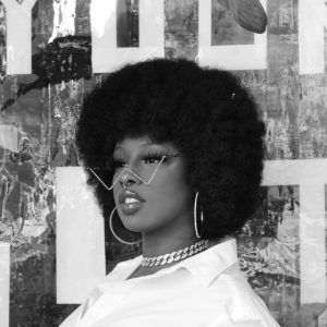 Black and white headshot of a woman with an Afro, wearing large hoop earrings and a light colored shirt.