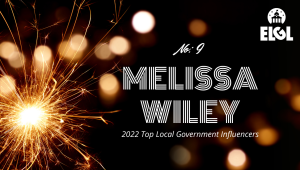 Gold firework sparkler and gold reflection spots on black background. White ELGL logo in upper right. Additional white text says "No. 9 Melissa Wiley 2022 Top Local Government Influencers."