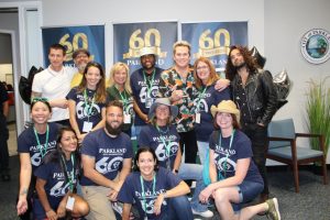 A group of people in T-shirts with the words "Parkland 60" on the front pose with the band Sugar Ray.