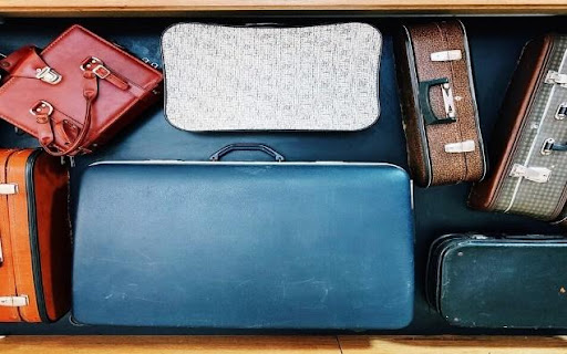 Top-down view of luggage standing next to each other, including a blue suitcase, red bag, white bag, brown case, and several more.